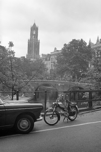 810948 Gezicht over de Oudegracht op de Domtoren te Utrecht; op de voorgrond een bromfiets en in het midden de Bakkerbrug.